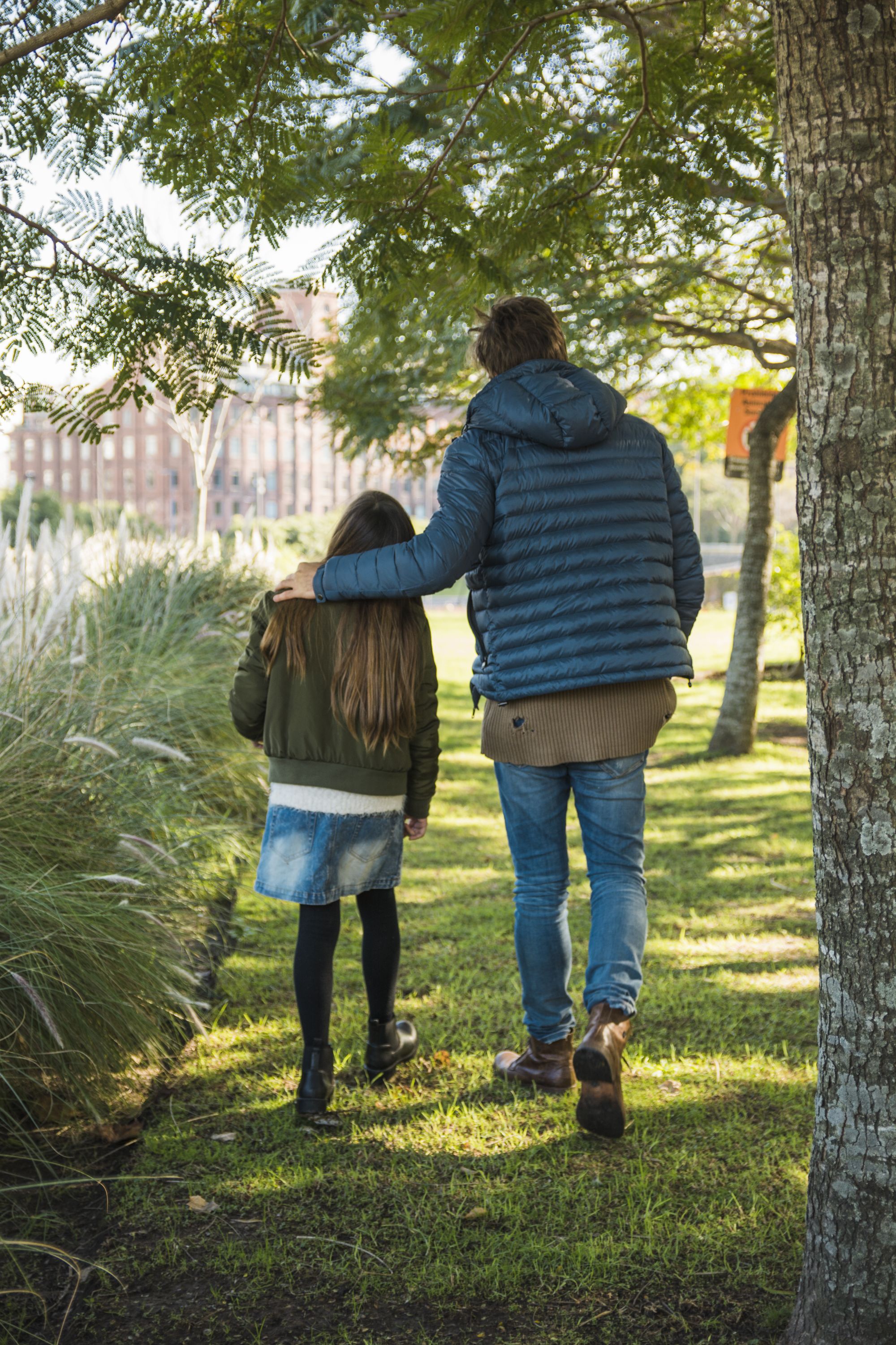 rear-view-father-daughter-walking-grass